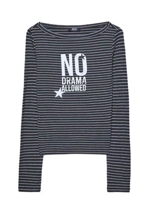 Dugi prugasti top s tamnosivim i svjetlosivim prugama te izrezom oblikom broda. Sadrži bijeli natpis "NO DRAMA ALLOWED" i grafiku zvijezde.