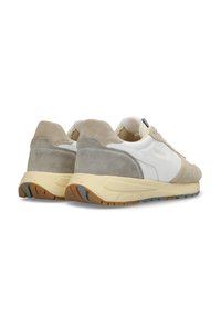 Sneakers da uomo con un mix di pelle bianca e suede grigio chiaro, caratterizzati da una texture morbida, una suola in gomma beige e un design minimalista.