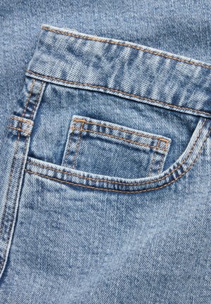 Denim jeans back pocket, light blue with visible texture. Stitched edges in orange thread. Small, rectangular shape. No embellishments.