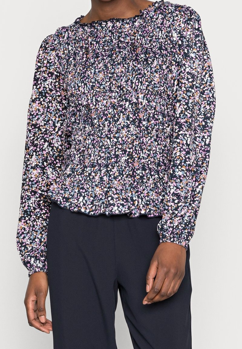 Maglia a maniche lunghe di colore blu navy con motivo floreale in rosa, viola e blu. Presenta un design arricciato nel corpetto e un orlo arruffato.