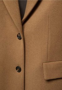 Bruine wollen blazer met een notch-revers, een borstzak en een enkele knoopsluiting, voorzien van een gladde textuur en subtiele glans.