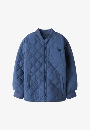 Gequilte jas in donkerblauw, met een ritssluiting aan de voorkant, een klein borstzakje en ribgebreide manchetten. Het ontwerp bevat ruitvormige stiksels.