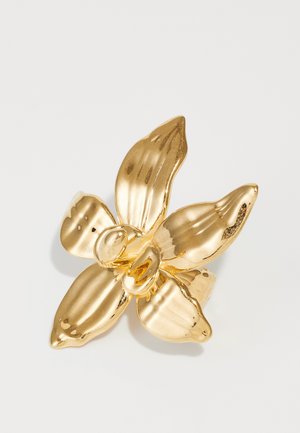 Gold flower-shaped ring with four textured petals, a smooth center, and a polished finish, reflecting light.