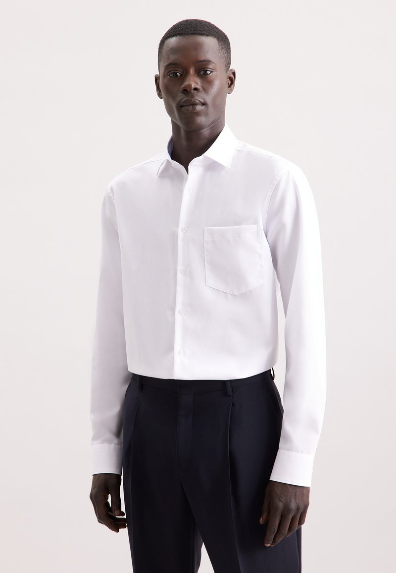 Witte lange mouwen shirt met een button-down kraag en een borstzak, gecombineerd met donkere broek, met een gladde textuur en een getailleerde pasvorm.