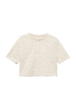 Veste blanche courte en tissu texturé avec un motif floral, dotée de manches courtes et d'un col rond, se fermant par des boutons sur le devant.