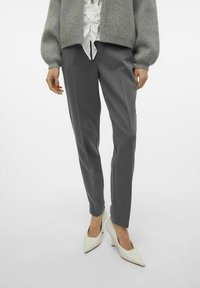 Pantaloni grigi su misura con una vestibilità slim, caratterizzati da una texture morbida e sottili righe verticali, abbinati a tacchi bianchi a punta.