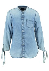 Camicia di jeans azzurro chiaro con colletto rialzato, chiusura a bottoni sul davanti, taschino singolo sul petto e maniche legate. Presenta dettagli di cucitura a vista.