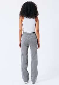 Grijze wijde spijkerbroek met een hoge taille, elastische tailleband en twee achterzakken. De stof heeft een zachte textuur met subtiele stikseldetails.