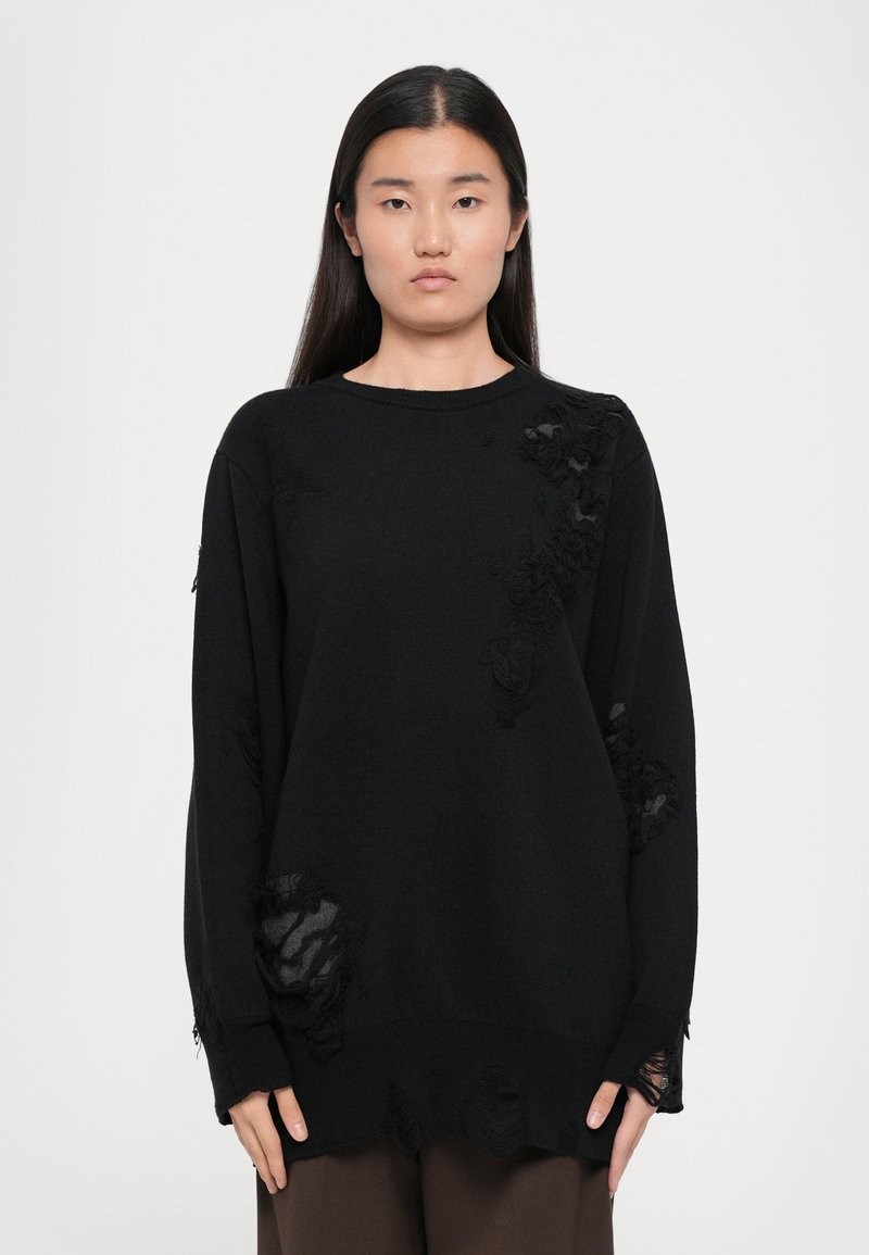 Black knit sweater with a loose fit, featuring distressed details and frayed edges. Long sleeves and a rounded neckline.