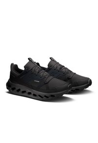 Baskets de sport noires avec une tige en tissu texturé, dotées d'un laçage et d'une semelle rembourrée avec des découpes pour plus de flexibilité.