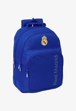 Niebieski plecak z wieloma zamykanymi na suwak przegródkami, logo Real Madrid i napisem "Real Madrid" na przedniej kieszeni.