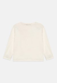 Top in cotone bianco a maniche lunghe con scollo rotondo, texture morbida e cuciture minime, presenta una parte posteriore semplice, senza decorazioni.