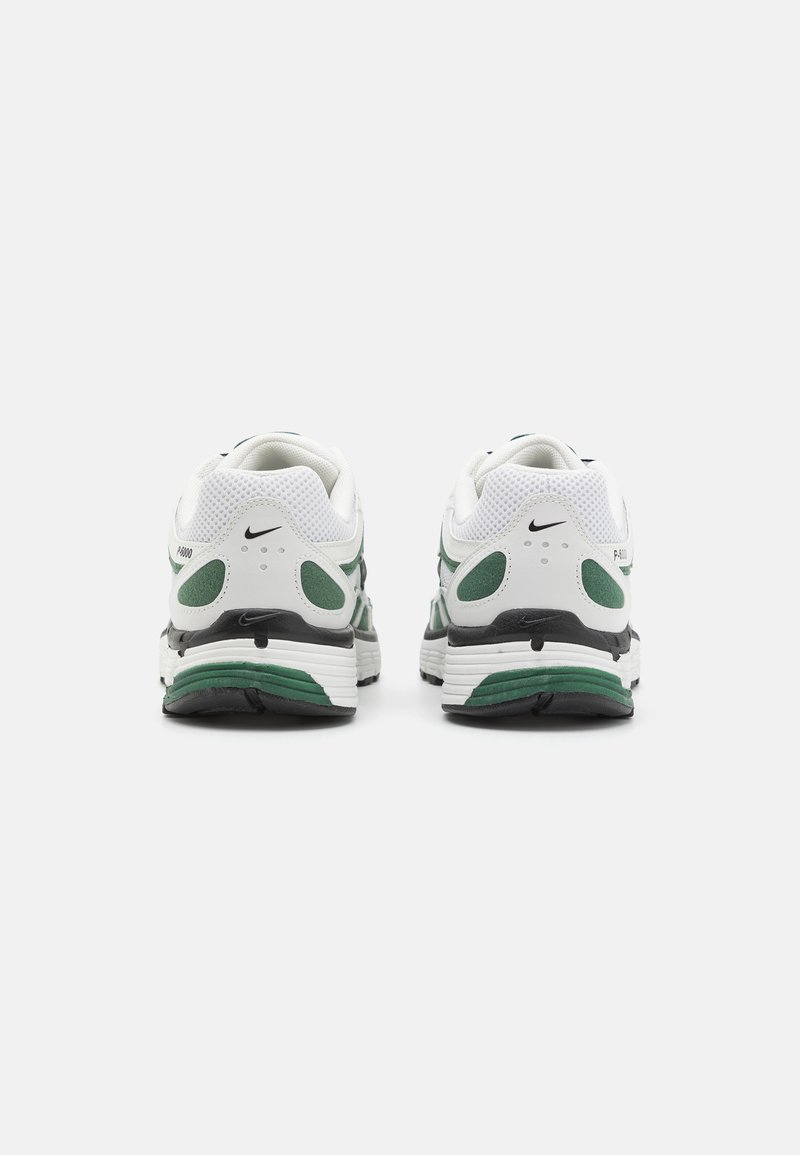 Baskets de sport blanches et vertes avec une tige en mesh, un col rembourré et une semelle à motifs. Comprend des accents noirs et un logo Nike.