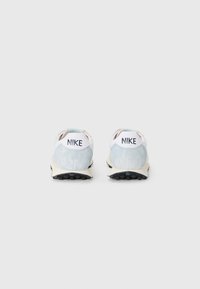 Nike sneakers med en lyseblå og hvid overdel, med polstret krave og sort gummisål. Bagsiden inkluderer brandlogo.