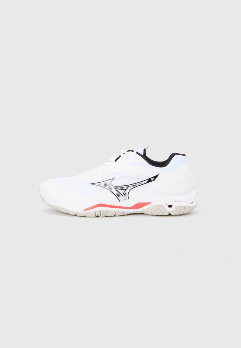 Fehér sportcipő texturált hálós felülettel, fekete díszítésekkel és piros peremmel a talpon. Elegáns kialakítású, lekerekített orral.