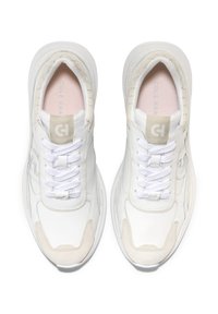 Bílé tenisky s hladkým koženým svrškem, texturovanými semišovými akcenty, kulatou špičkou a plochými tkaničkami. Obsahují nenápadné logo poblíž jazyka.