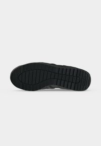 Semelle de chaussure noire avec des rainures horizontales et verticales profondes pour la traction, affichant le nom de la marque embossé près de la zone du talon.