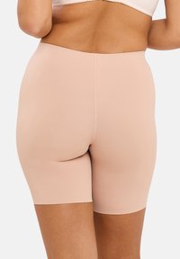 Shorts de shapewear beiges, longueur mi-cuisse, fabriqués en matériau lisse et extensible avec un design sans couture et sans matériel ou motifs visibles.