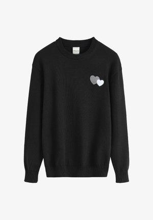 Pull en tricot noir avec un col rond. Présente deux cœurs brodés en gris et blanc sur le côté gauche. Poignets et ourlet côtelés.