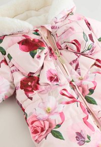 Lys pink pufferjakke prydet med farverige blomsterprint, med en hyggelig krave foret med faux pels og lynlås.