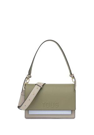 Bolso de cuero verde oliva para hombro con correa beige ajustable, herrajes dorados y "TOUS" estampado en la solapa frontal. Diseño minimalista.