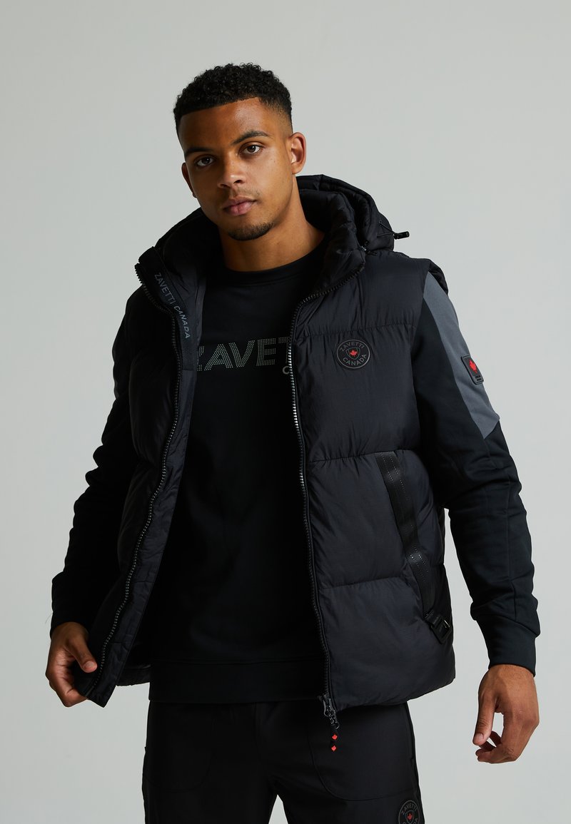 Μαύρο μπουφάν με επένδυση και κουκούλα, διαθέτει μπροστινό φερμουάρ, δίχρωμες πάνελ και λογότυπο στο αριστερό στήθος. Υφασμάτινη επιφάνεια.