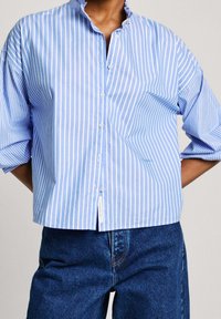Blue and white striped button-up shirt with a mandarin collar and wide sleeves; made of light fabric with a smooth texture.
