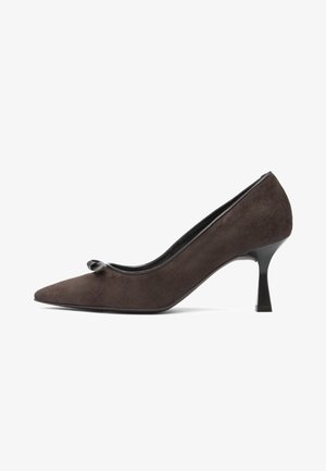 Dark brown suede women's high heel shoe with pointed toe, small bow detail, and slender black heel against white background.