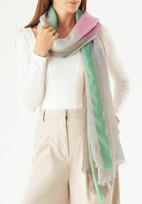 Lichtgewicht, meerkleurige sjaal met tinten roze, groen en beige; zachte textuur met rafelige randen; losjes om de nek gedragen.