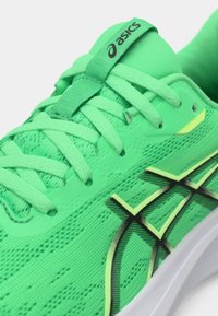 Grønn treningssko med teksturert mesh-overdel, flate lisser, svarte detaljer og hvit såle. Har fremtredende merkevare på tungen.
