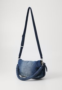 Džínová taška přes rameno s měkkým, kulatým tvarem, tmavě modré barvy, strukturovanou tkaninou a dvojitými popruhy: jeden plochý a jeden spirálový pro lepší úchop.