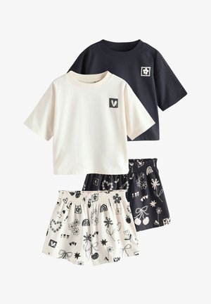 Deux chemises à manches courtes, une noire avec un patch fleur, une blanche avec un patch cœur, assorties à des shorts à motifs floraux noirs et blancs assortis.