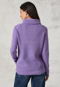 Lila gerippter Pullover mit hohem Kragen, langen Ärmeln und tailliertem Schnitt. Der Stoff wirkt weich und strukturiert.