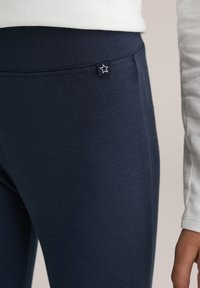 Tengerészkék leggings puha, rugalmas anyagból, a derékszíjon kis csillag címkével és sima felülettel.