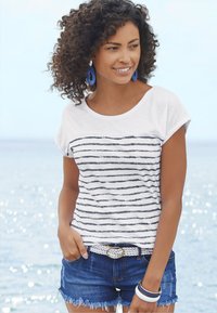 Svītrainā baltā T-kreklu ar tumši ziliem svītrām, saskaņots ar džinsa šortiem. Aksesuāri ietver pītās jostas un daudzkrāsainas aproces.