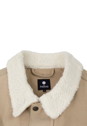 Beige jasje met een fluffy witte sherpa kraag, voorzien van een knoopsluiting en een zwart merklabel aan de binnenkant. Textuur details zijn zichtbaar.