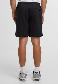 Černé bavlněné šortky s elastickým pasem, bočními kapsami a malou zipovou kapsou na zadní straně. Obsahují decentní logo.