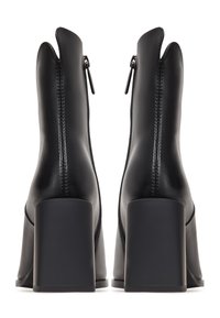 Schwarze Leder-Ankle-Boots mit einem hohen, klobigen Absatz. Mit einem Reißverschluss vorne und einer einzigartigen gewellten Öffnung oben. Glatte Textur.