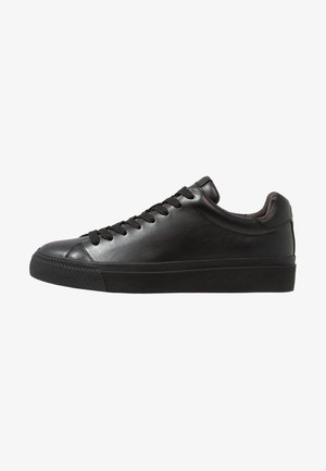 Black low-top leather sneaker with black laces and rubber sole, shown from the inner side on a white background.