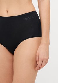 Svart bomullsbrief med høy midje. Har en glatt tekstur og subtil logo "BORG" preget på midjebåndet.