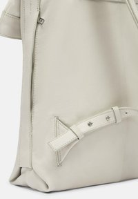 Jasnoszara skórzana torba z bocznym zamkiem, złożoną konstrukcją i paskiem z metalowymi akcentami. Gładka tekstura z detalami przeszyć.