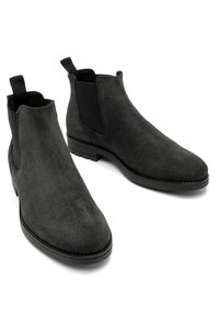 Czarne zamszowe botki Chelsea z elastycznymi bocznymi panelami, zaokrąglonym noskiem i teksturowanym materiałem. Posiadają niski obcas i pętelkę ułatwiającą zakładanie.