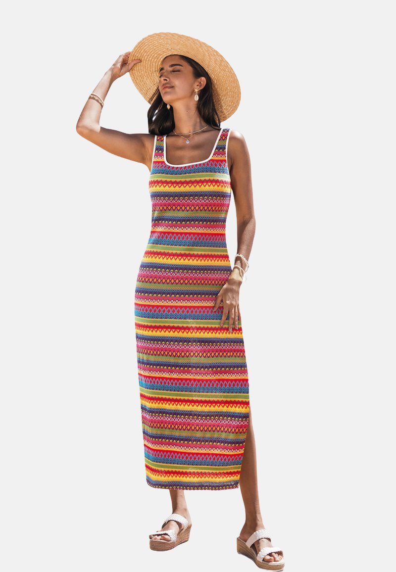 Colorful patterned maxi dress with a square neckline, featuring stripes in red, yellow, blue, and purple; has a side slit and flat sandals.
