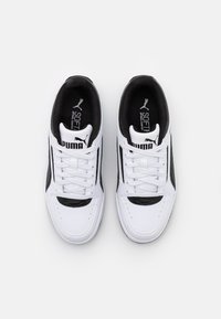 Baskets blanches avec accents noirs, tige en cuir et synthétique, design à lacets, col rembourré et logo Puma sur la languette et le côté.