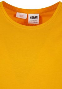 Gul t-shirt med rund hals, med Urban Classics mærke og størrelse 122/128 (US 8), fremstillet i Bangladesh, og en "Keep away from fire" advarselsmærkat.