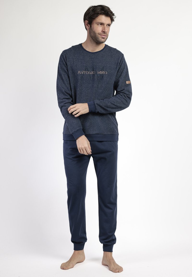 Conjunto de lounge en azul marino de algodón que incluye una camiseta de manga larga texturizada con logo y pantalones de chándal a juego con puños elásticos.