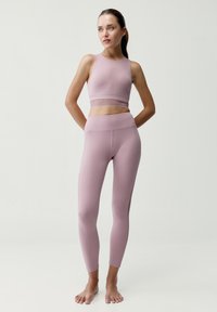 Světle fialový sportovní set skládající se z upnutého crop topu a legín s vysokým pasem, oboje s hladkou texturou a bezešvým designem.