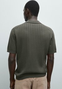 Short-sleeve, olive green knitted sweater with vertical ribbed texture, a flat collar, and a fitted hem. View from the back.