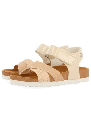 Sandales beiges avec des sangles en tissu tissé, une finition brillante en vernis et une semelle intérieure rembourrée ; dotées de fermetures réglables en Velcro et d'une semelle texturée.