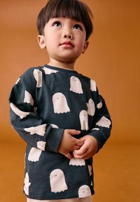 Dunkelgraues Langarmshirt mit einem Muster aus lächelnden weißen Geistern. Der Stoff wirkt weich und hat eine lockere Passform mit gerippten Bündchen.